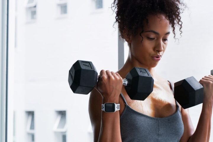 Woman performs biceps curl exercise with dumbbells