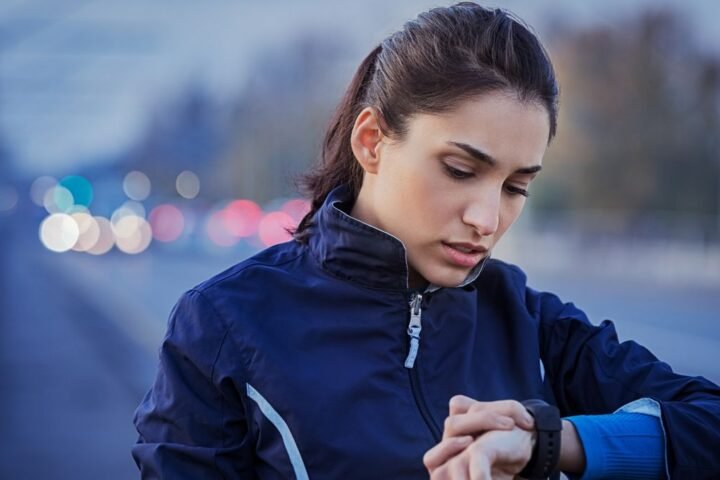 Woman wearing running jacket looks at her running watch