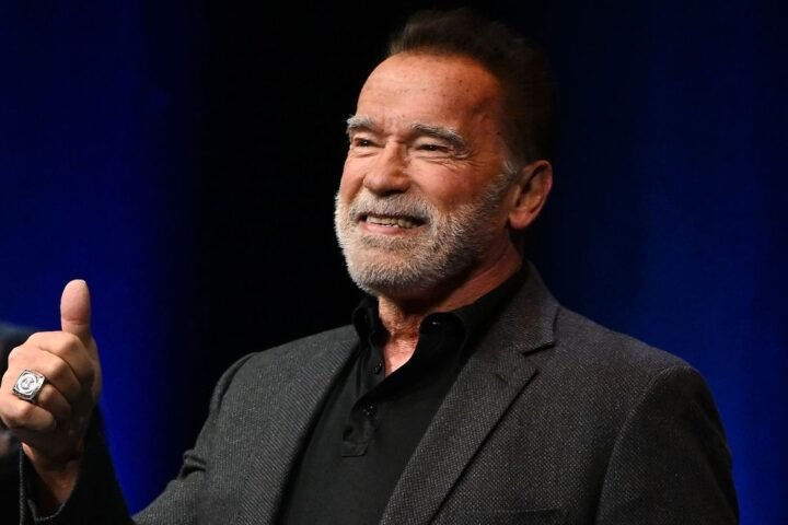 Arnold Schwarzenegger smiling and giving a thumbs up, he is arriving onstage at an Evening with Arnold Schwarzenegger presented by Fane at London Palladium on October 24, 2023