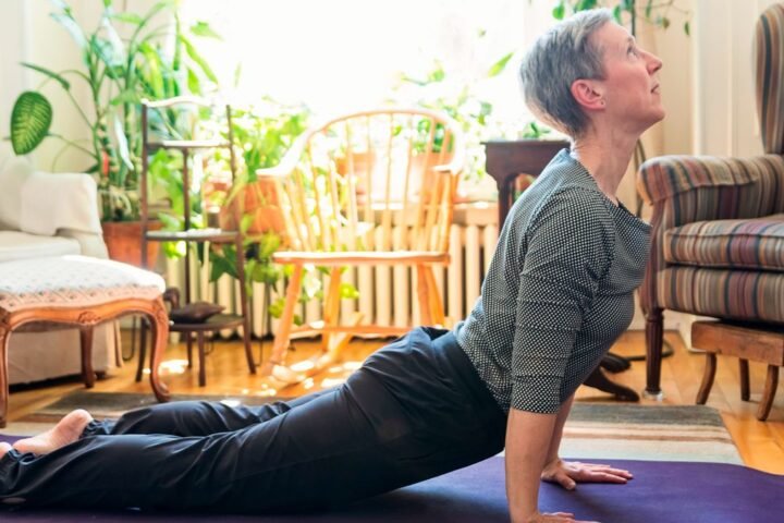 Woman performs swan Pilates move at home